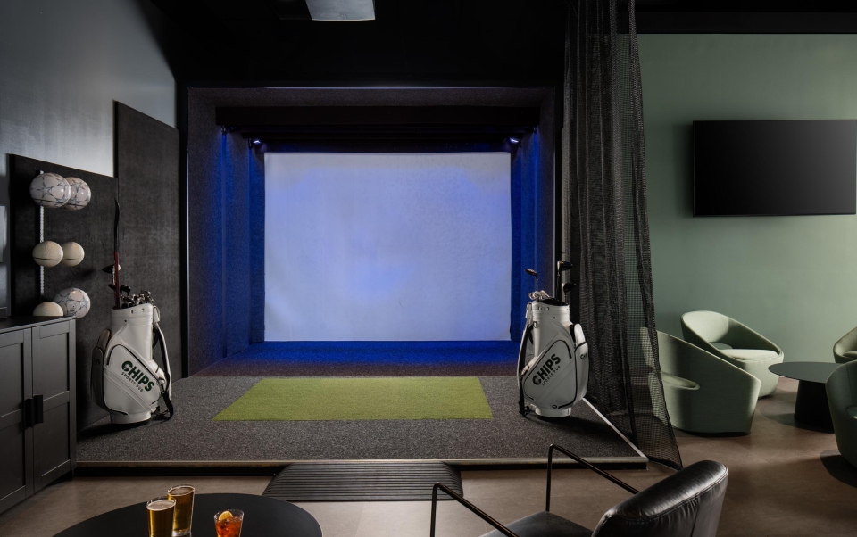 A room with a golf club and virtual game screen